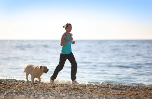 Picture for August Astro Sale used is Woman and dog pictured jogging on a beach